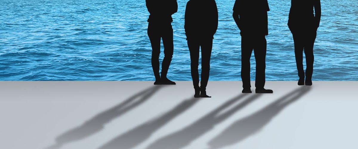 Four people are standing in front of the ocean