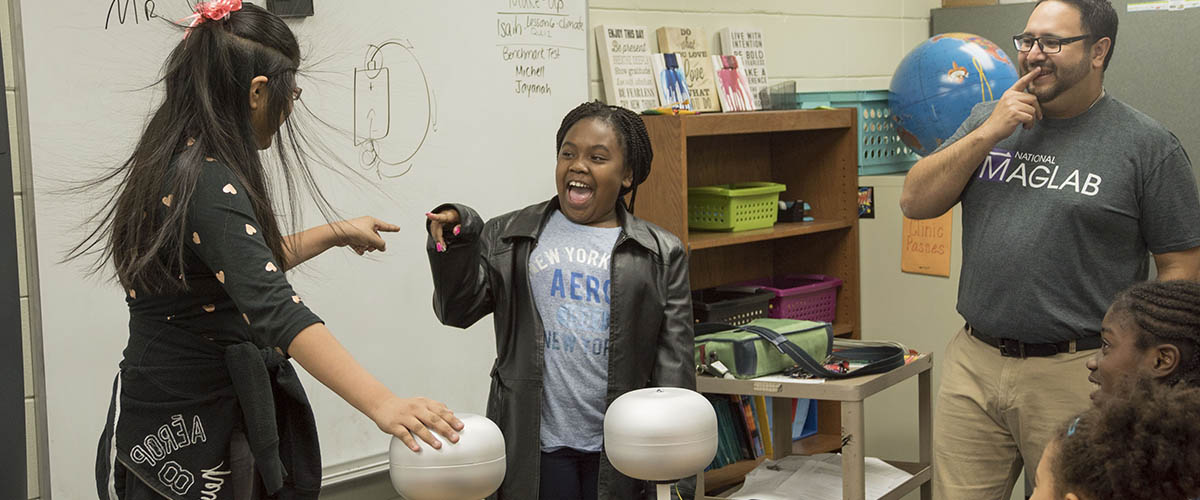 Carlos R. Villa helps students explore static electricity using a Van de Graaff generator during a visit to a local school.