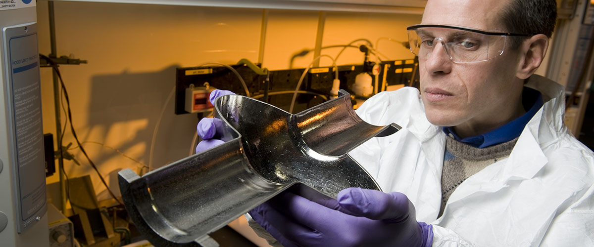 Lance Cooley examines the cross-section of an RF cavity, a critical component of a particle accelerator